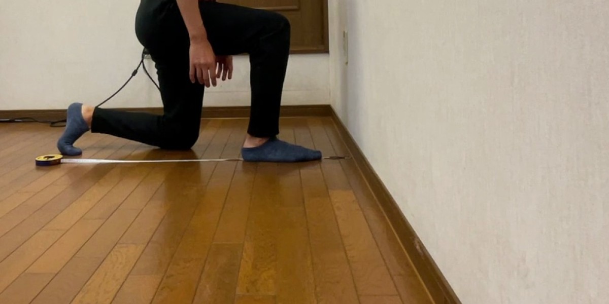 壁の前で片膝立ちになり、巻尺でつま先と壁の距離を確認している様子